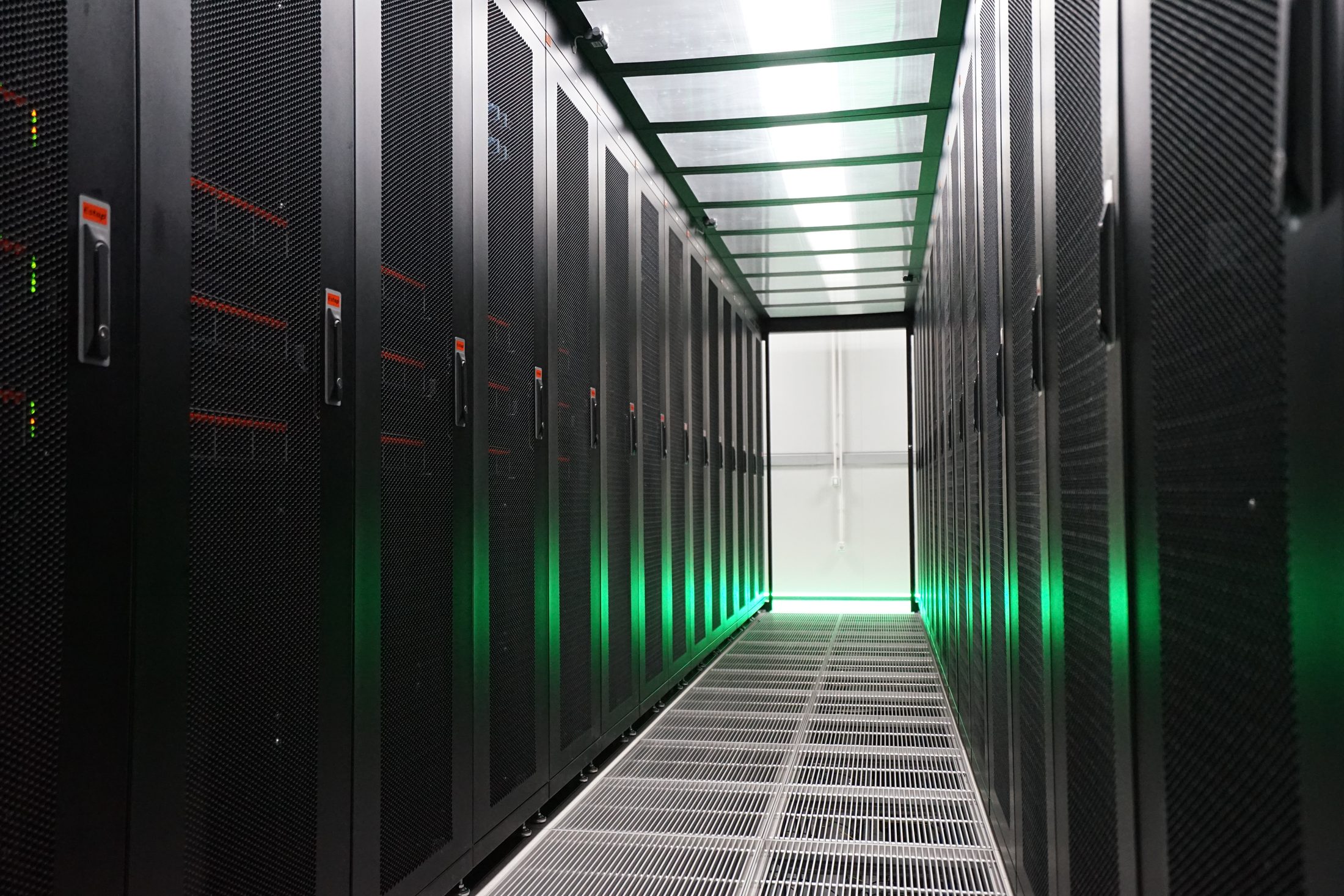 Cold-aisle containment corridor in EvoDC-1 with green light and perforated floor tiles