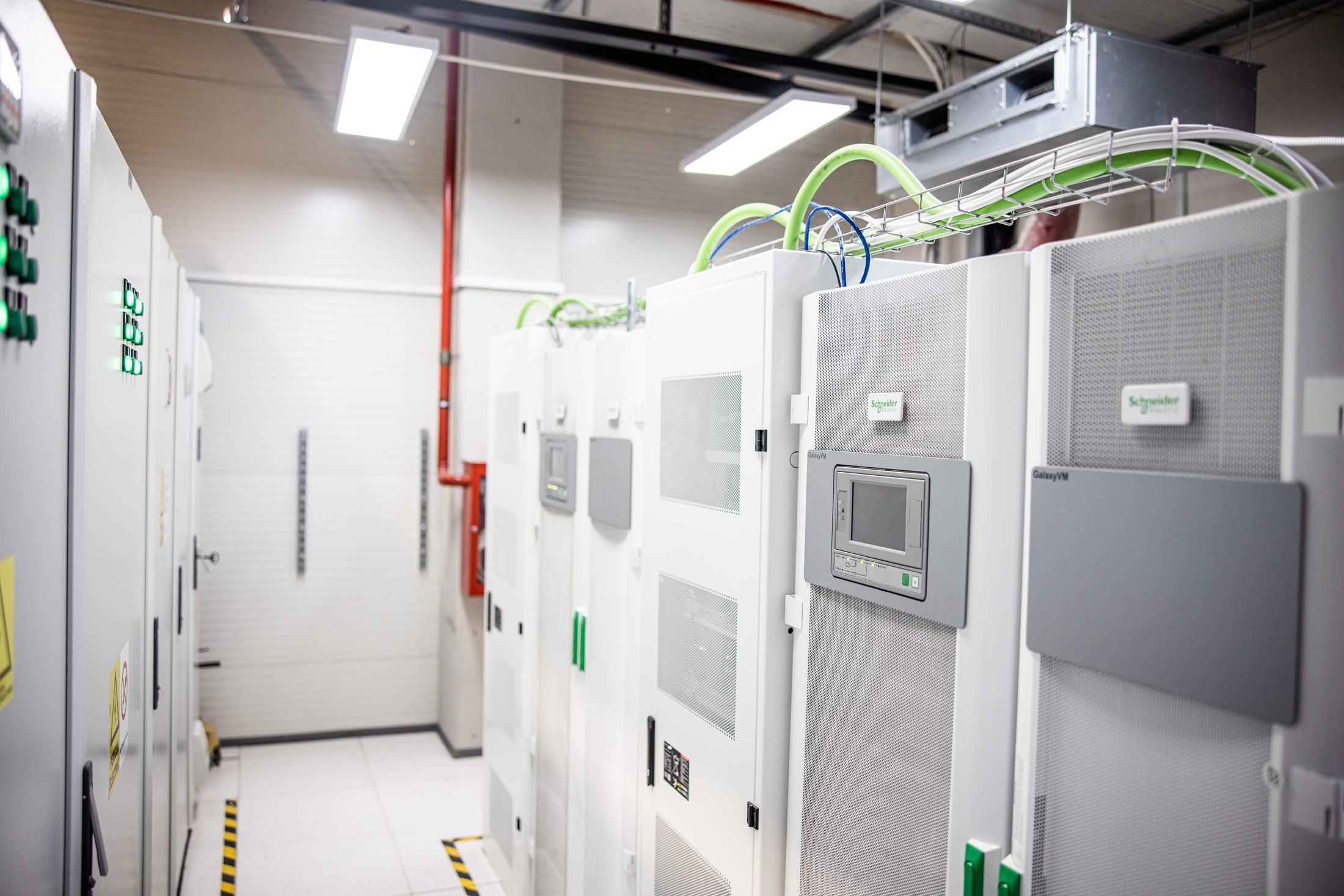 UPS room with white Li-Ion double-conversion UPS cabinets and green cable trays