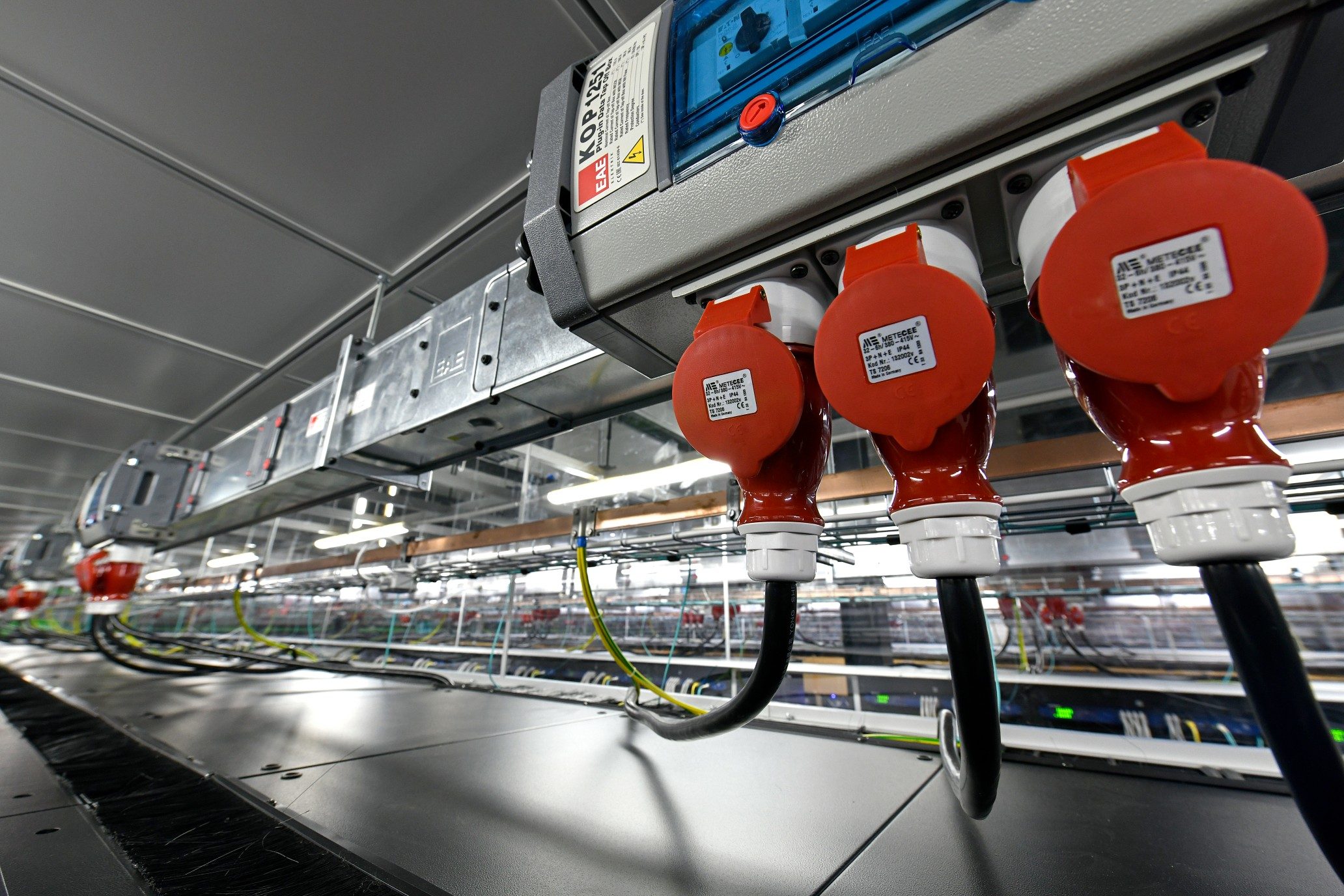 Red 3-phase sockets on busbar trunking above a rack row