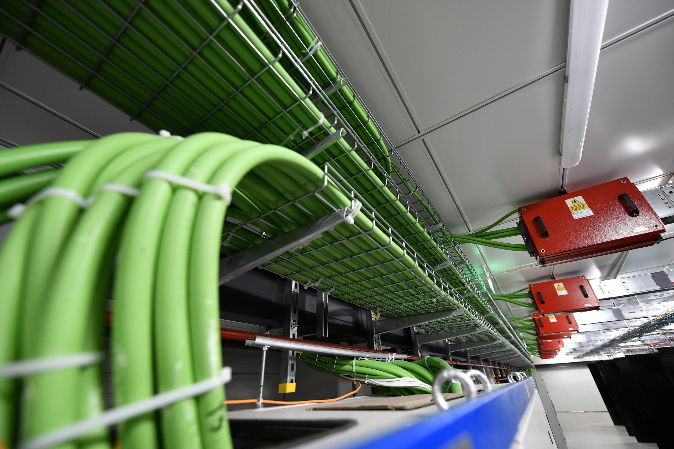Green power cables in mesh trays with red junction boxes