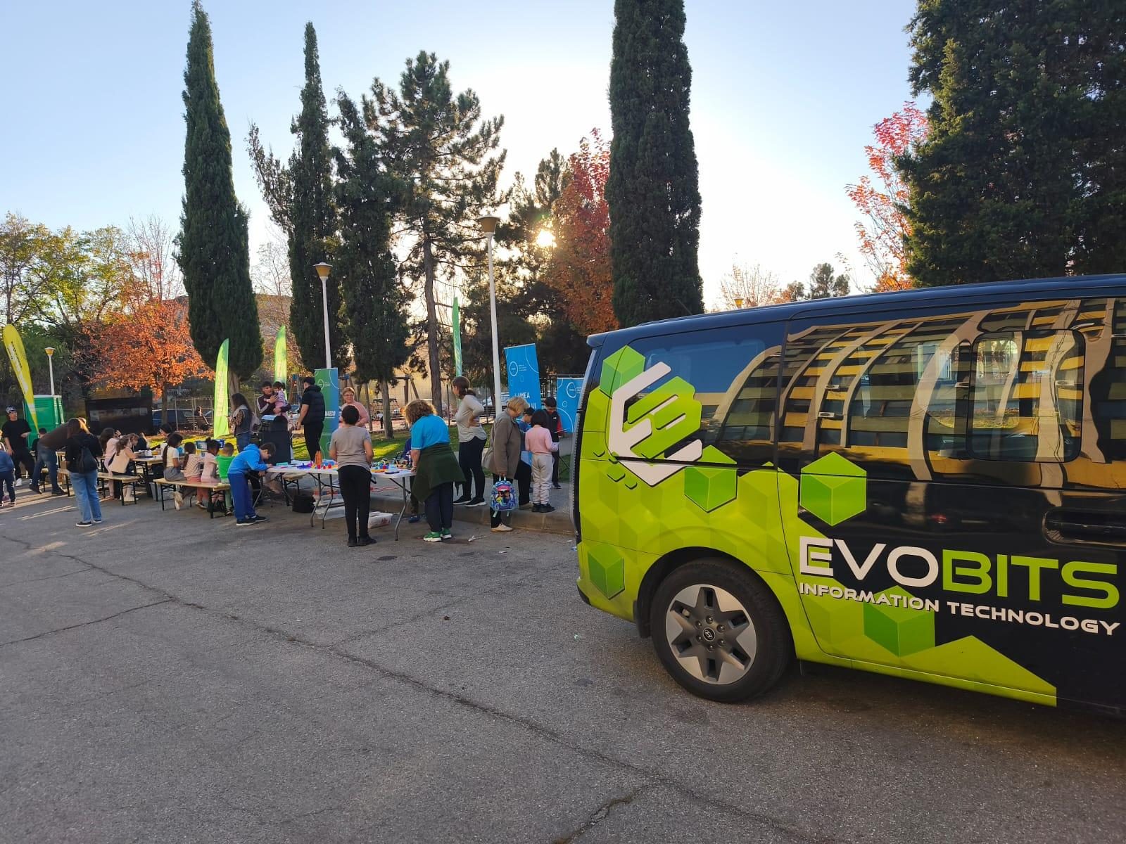 Caravana For Life: children and volunteers at outdoor workshop tables next to the Evobits minibus
