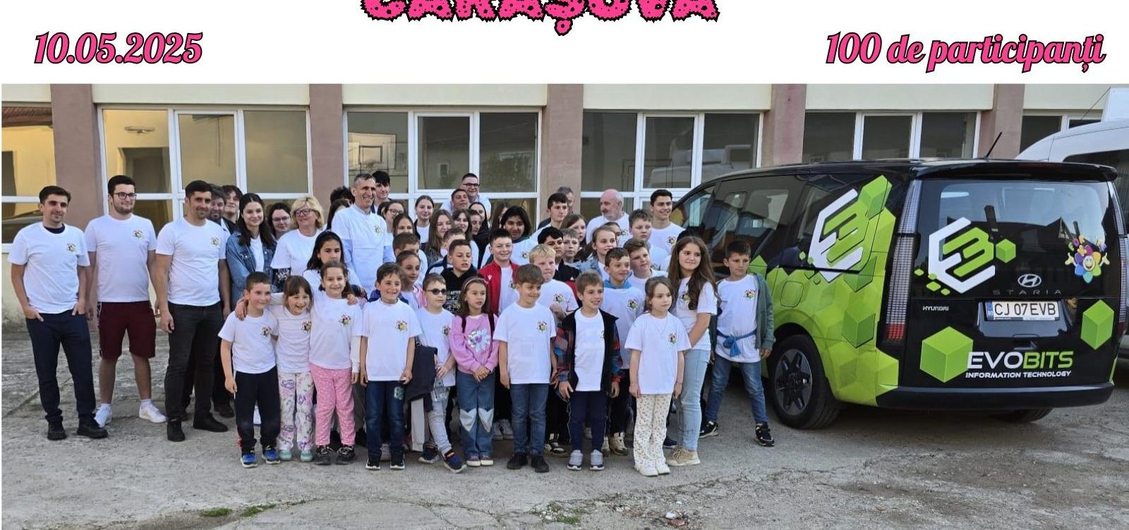 Group photo of children and volunteers in front of a village school with the Evobits minibus