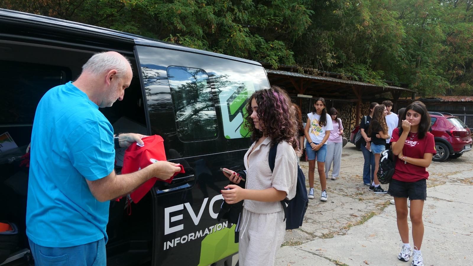 Professor Ovidiu Bădescu handing out For Life shirts to students next to the minibus
