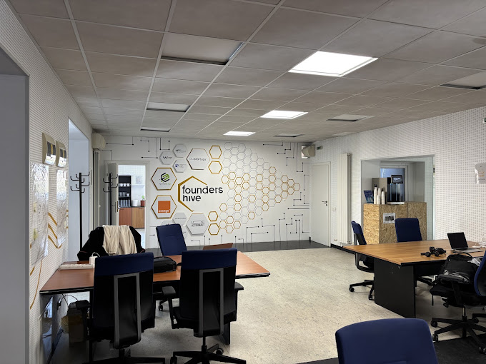 Founders Hive workspace inside the Evobits headquarters: desks, chairs and the hexagon wall with the Founders Hive logo
